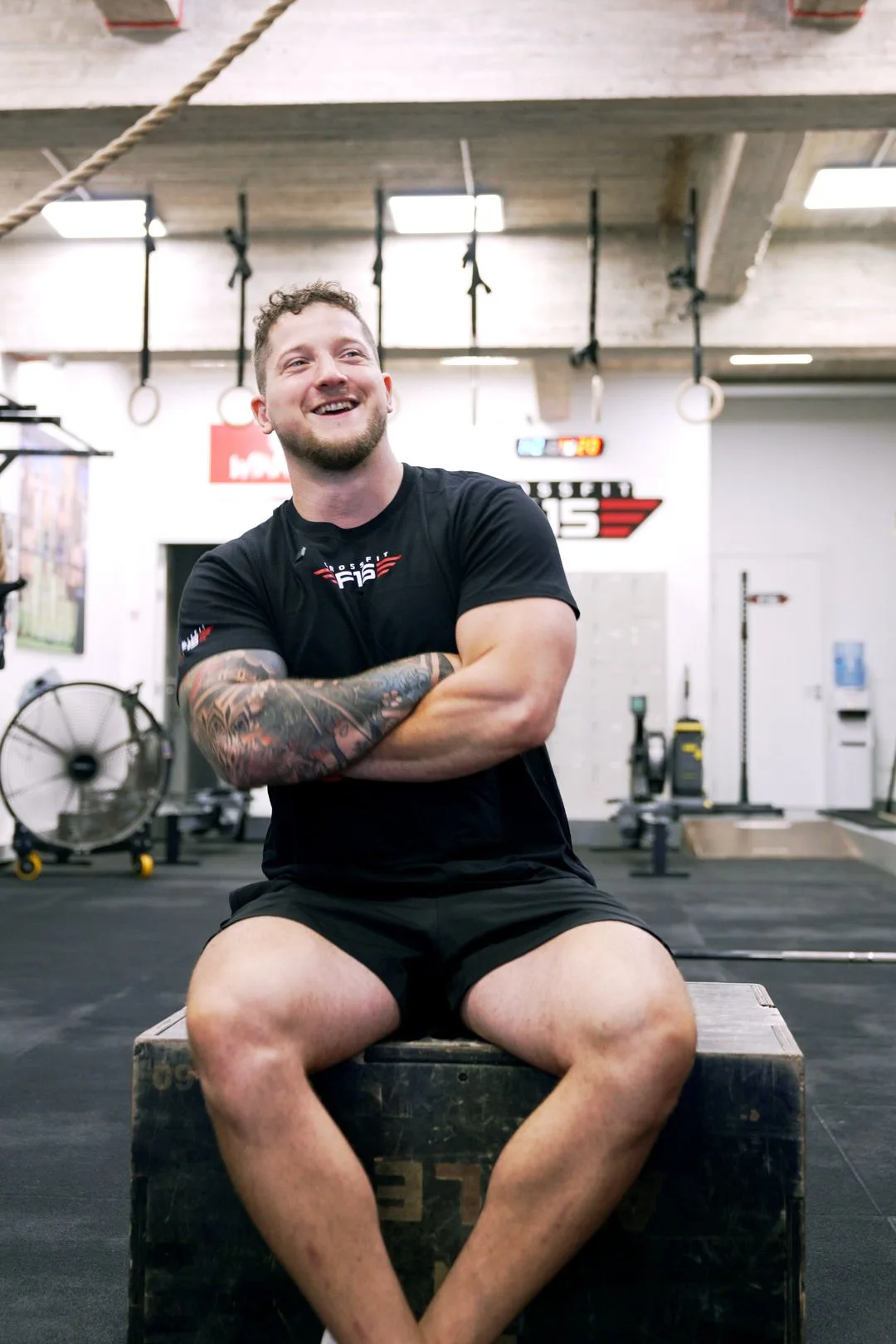 Smiling athlete in F15 t-shirt sitting on box at personal training Msida gym